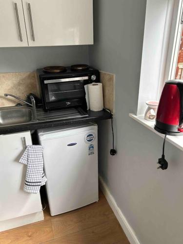 uma cozinha com um micro-ondas em cima de um frigorífico em Studio apartment em Londres