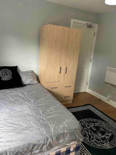 um quarto com uma cama e um armário de madeira em Studio apartment em Londres