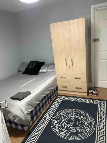 um quarto com uma cama, um armário e um tapete em Studio apartment em Londres