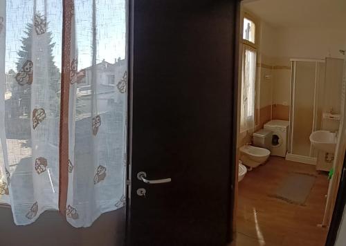 puerta a un baño con aseo y ventana en Casa Bianca, en Tortona