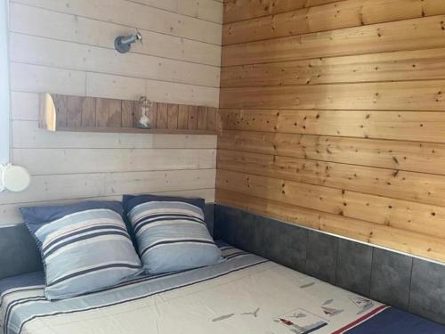 a bed with two pillows in a room with wooden walls at Chalet au bord de l'eau, terrasse privée, pêche, baignade, nature et détente, animaux acceptés - FR-1-489-359 in Pierrefitte-sur-Loire