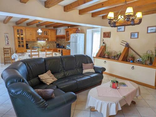 Il comprend un salon avec un canapé en cuir noir et une cuisine. dans l'établissement Maison familiale avec jardin clos, accès rivière et Wi-Fi, proche verdure et activités en Charente - FR-1-653-117, à Saint-Genis-dʼHiersac