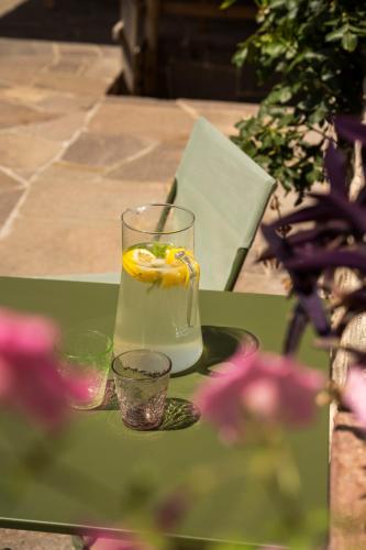 a drink on a table with two glasses and flowers at B&B Le Molinare Home Relax in Varda