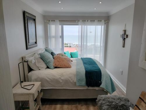 1 dormitorio con cama con almohadas y ventana en Holiday Home With Sea Views, en Jeffreys Bay