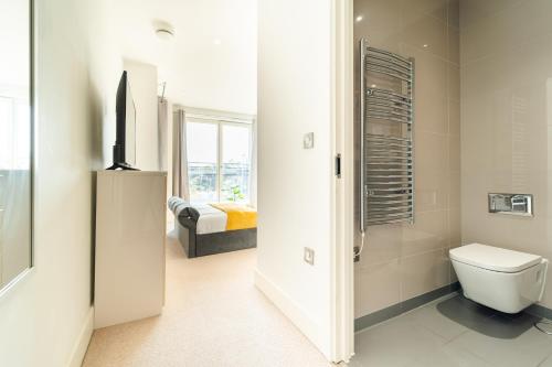 a white bathroom with a toilet and a bedroom at Luxury Greenwich 2Bed 2Bath Apt - Sleep 6 Guest- 1 min from station - close to Greenwich Maritime- Playstation provided in London