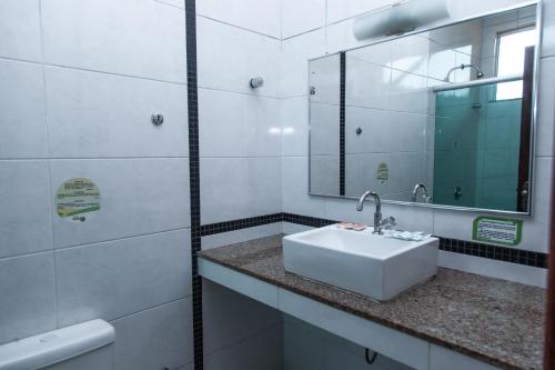 a white bathroom with a sink and a mirror at Hotel Equinocios Executive in Barcarena