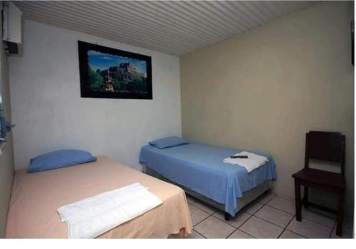 Hotel El Castillo del Puerto في بويرتو باريوس: غرفة نوم بسريرين وصورة على الحائط