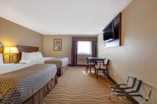 Una habitación de hotel con dos camas y un televisor. en Best Western High Road Inn, en Edson