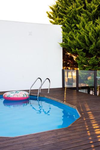 a swimming pool on a wooden deck with a tree at KABACEIRA VILLAGE in Atalaia