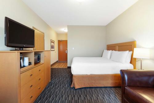a hotel room with a bed and a flat screen tv at Best Western Grande Prairie in Grande Prairie