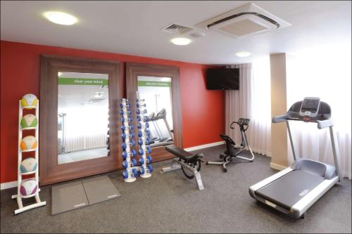 a gym with exercise equipment in a room with red walls at Hampton by Hilton Birmingham Broad Street in Birmingham