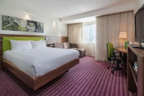 a hotel room with a large bed and a desk at Hampton by Hilton Birmingham Broad Street in Birmingham