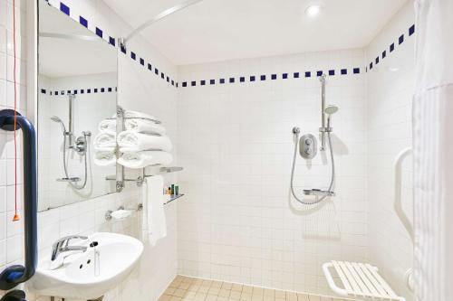 a white bathroom with a shower and a sink at Hilton Garden Inn Bristol City Centre in Bristol