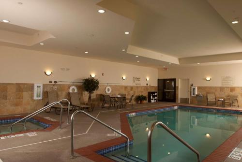 a swimming pool in a hotel with tables and chairs at Hampton Inn Tomah in Tomah