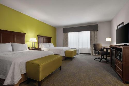 a hotel room with two beds and a flat screen tv at Hampton Inn & Suites Mishawaka/South Bend at Heritage Square in South Bend