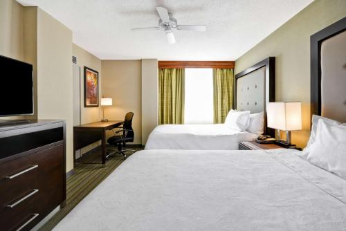 a hotel room with two beds and a flat screen tv at Homewood Suites Dulles-International Airport in Herndon
