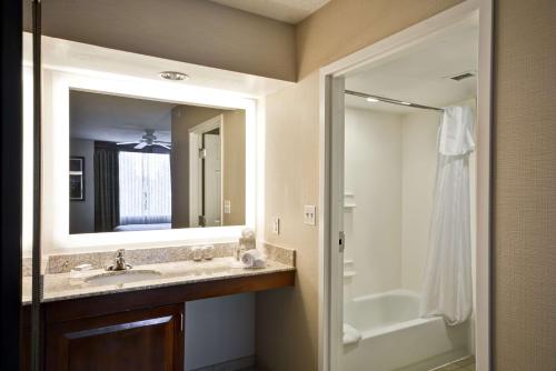 La salle de bains est pourvue d'un lavabo, d'une baignoire et d'un miroir. dans l'établissement Homewood Suites Dulles-International Airport, à Herndon