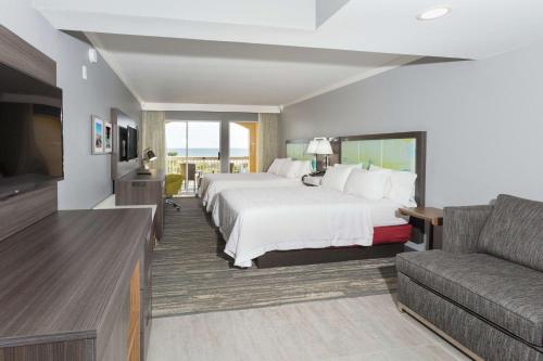 a hotel room with a large bed and a couch at Hampton Inn Saint Augustine Beach in Saint Augustine Beach