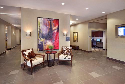 a lobby with two chairs and a painting on the wall at Homewood Suites Calgary Airport in Calgary