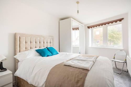a white bedroom with a large bed with blue pillows at The Dartford Lodge - Free Parking in Kent