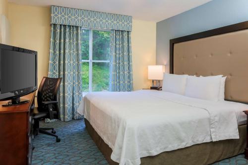 a hotel room with a bed and a television at Homewood Suites Nashville Airport in Nashville