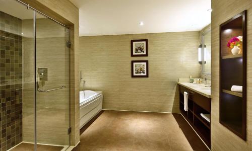 a bathroom with a shower and a tub and a sink at Hilton Alexandria King's Ranch Hotel in Alexandria