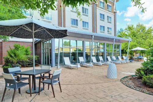 a patio with chairs and a table with an umbrella at DoubleTree by Hilton Hotel Baton Rouge in Baton Rouge