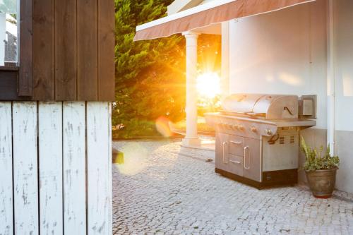 a grill on a patio with the sun in the background at KABACEIRA VILLAGE in Atalaia