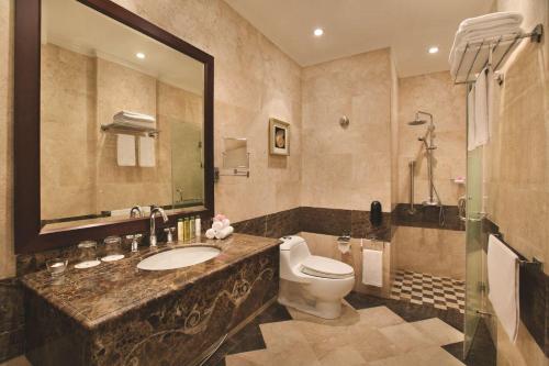 a bathroom with a toilet and a sink and a mirror at DoubleTree by Hilton Dhahran in Al Khobar