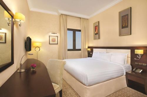 a hotel room with a white bed and a desk at DoubleTree by Hilton Dhahran in Al Khobar