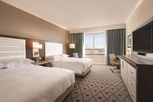 a hotel room with two beds and a flat screen tv at Hilton Los Angeles/San Gabriel in San Gabriel