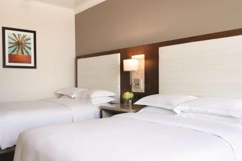 two beds in a hotel room with white sheets at Hilton Los Angeles/San Gabriel in San Gabriel