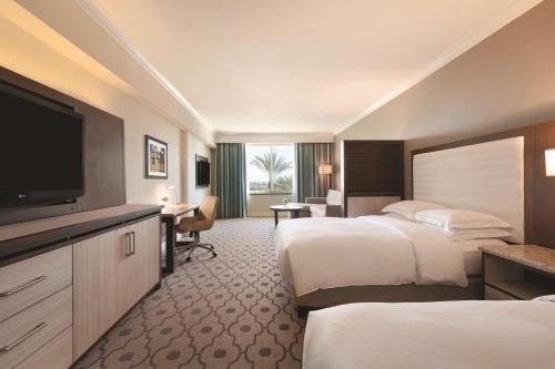 a hotel room with two beds and a flat screen tv at Hilton Los Angeles/San Gabriel in San Gabriel