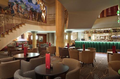 un ristorante con tavoli e sedie e una scala di Hilton London Paddington a Londra