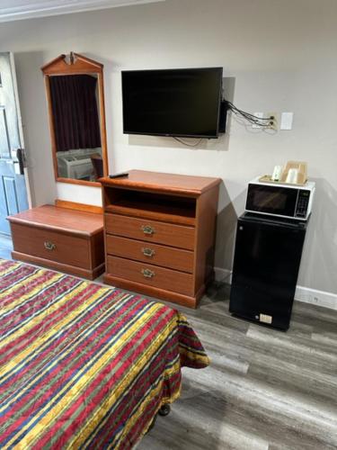 a bedroom with a tv and a dresser and a bed at Chino Motel in Chino