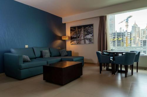 a living room with a blue couch and a table at Hampton by Hilton Panama in Panama City