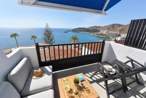 a balcony with a couch and chairs and the ocean at Los Canarios 630 by VillaGranCanaria in Patalavaca