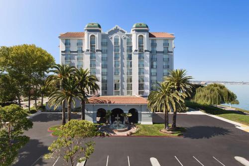 a large building with palm trees in front of a parking lot at Embassy Suites San Francisco Airport Waterfront in Burlingame