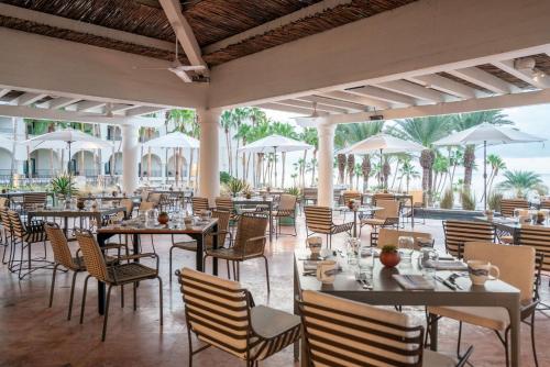 un restaurante con mesas, sillas y sombrillas en Hilton Los Cabos, en San José del Cabo