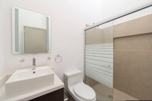 Un baño con inodoro, lavabo y ducha. en The Smurfs Townhome. Pool / FREE parking., en Puerto Morelos