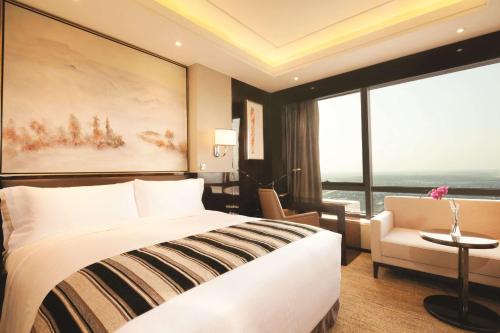 a hotel room with a bed and a chair and a large window at DoubleTree By Hilton Anhui in Suzhou