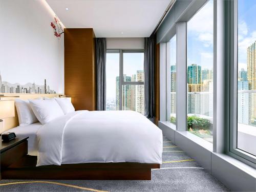 a bedroom with a large bed and large windows at Hilton Garden Inn Hong Kong Mongkok in Hong Kong