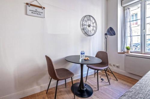 a table and chairs in a room with a clock on the wall at L'industriel Brestois in Brest