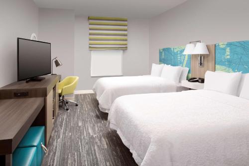 a hotel room with two beds and a flat screen tv at Hampton Inn Miami Airport East in Miami