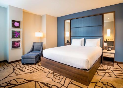 a bedroom with a large bed and a blue chair at Hilton Garden Inn Bogota Airport in Bogotá