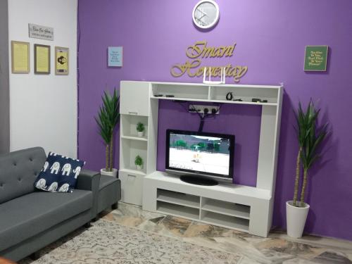 - un salon avec une télévision et un mur violet dans l'établissement Imani Homestay Beach Gateway Bagan Lalang, à Bagan Lalang