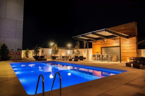 a swimming pool in a backyard at night at Hilton Garden Inn Aguascalientes in Aguascalientes