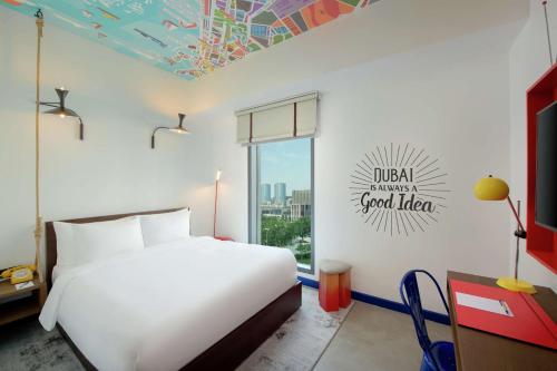 a bedroom with a white bed and a window at Hampton by Hilton Dubai Al Seef in Dubai