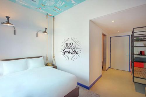 a bedroom with a white bed and a sign on the wall at Hampton by Hilton Dubai Al Seef in Dubai