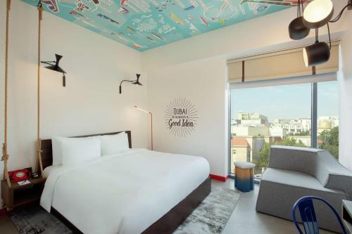 a bedroom with a bed and a chair and a window at Hampton by Hilton Dubai Al Seef in Dubai